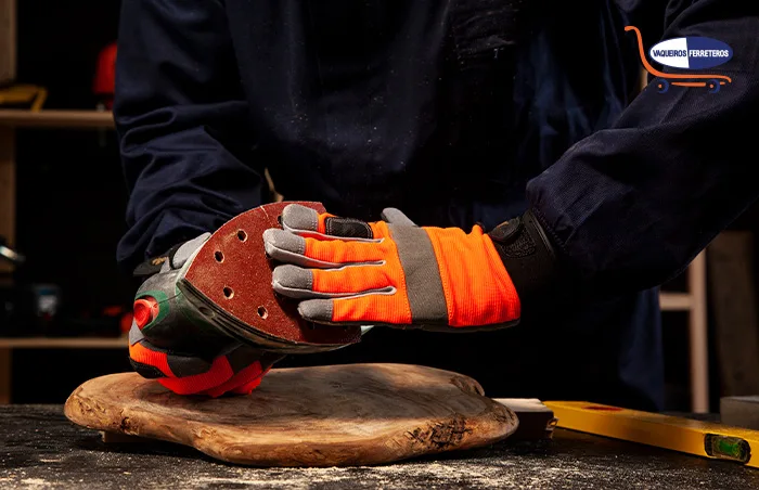 Trabajador con guantes de protección personal alistando la lijadora que va a usar.