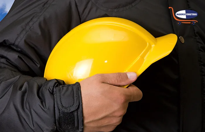 Torso de un trabajador que sostiene su equipo de protección personal para la cabeza.