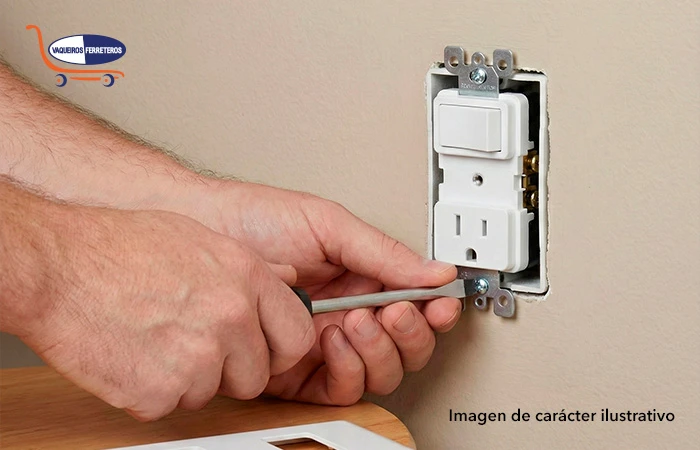 Manos desatornillando la tapa de un apagador/contacto.